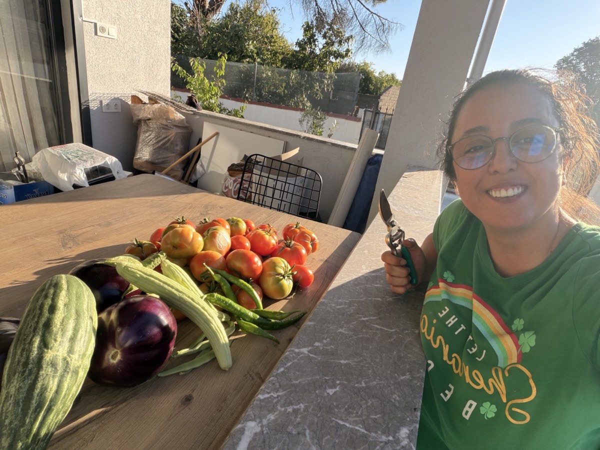 Burcu beside tomatoes, peppers, eggplants and melons harvested from her garden
