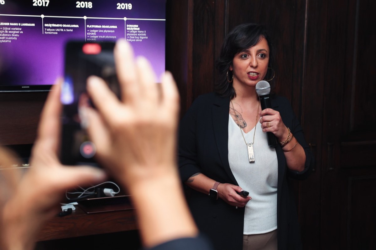 Burcu giving a Ledger presentation while an attendee records on a phone