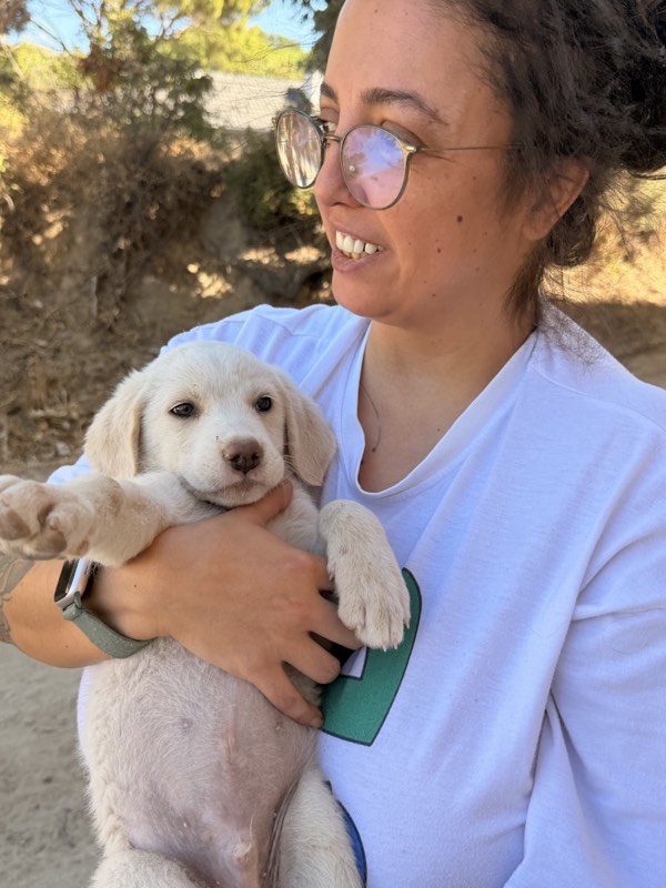 Burcu holding a white puppy outdoors in the village